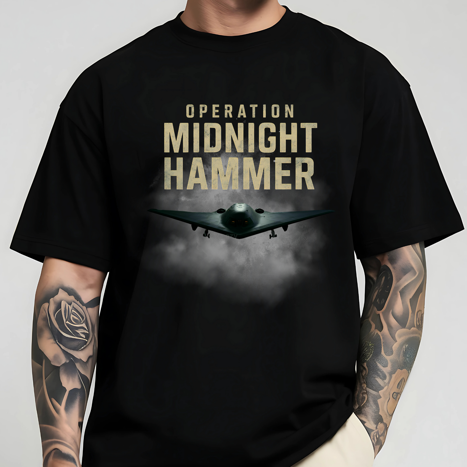 Man wearing Operation Midnight Hammer military graphic shirt with fierce B-2 Spirit bomber front and center. Bold airstrike-themed design perfect for patriots, veterans, and supporters of American air power and defense.