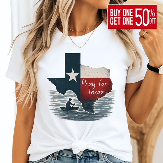 White unisex Pray for Texas T-shirt featuring a distressed Texas flag graphic with "Pray for Texas" text and a silhouette of a person in a canoe. Casual women's outfit paired with denim, perfect for Texas pride and support.